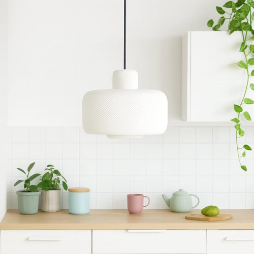 Modern kitchen with a white pendant light, wooden countertop, and decorative items.