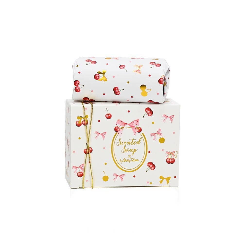 A 100g bar of Cherry Bloom scented soap by SoapTales, presented in a luxury white gift box featuring illustrations of red cherries, pink bows, and delicate gold details.