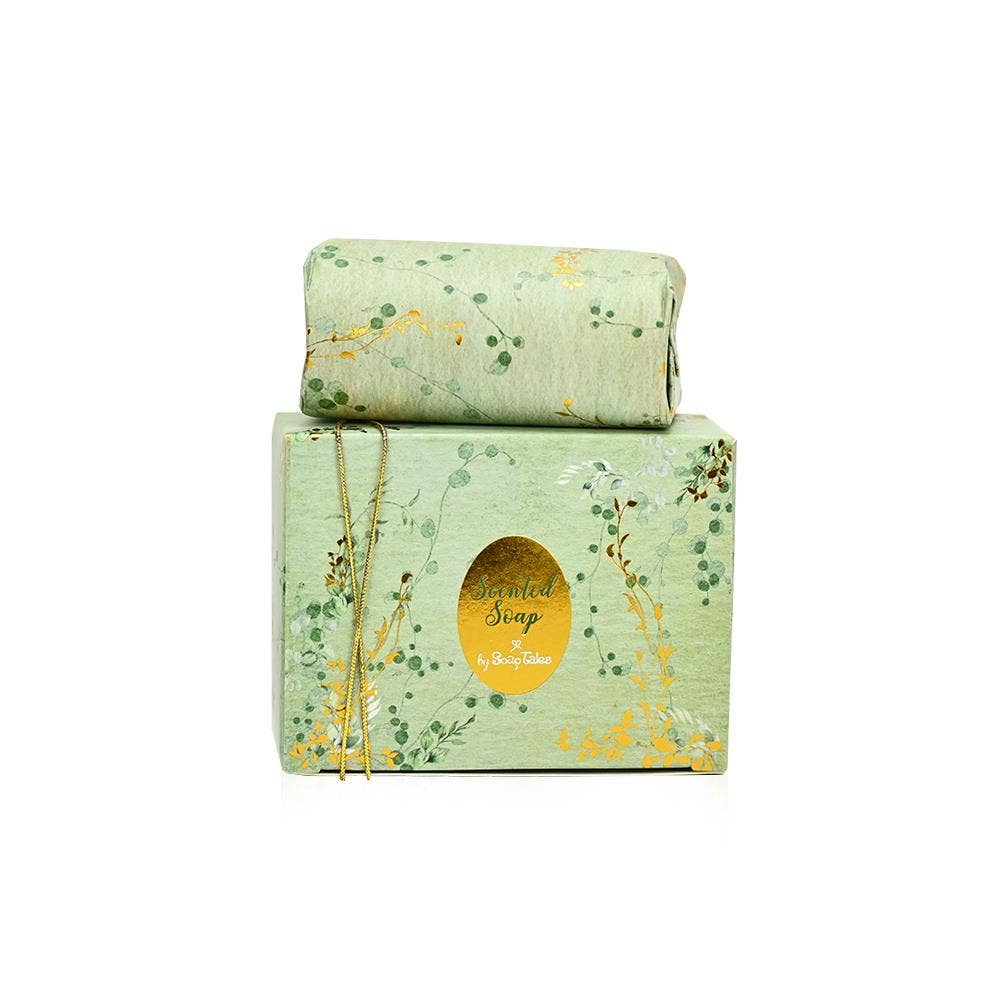 A 100g bar of SoapTales Eden scented soap in a luxury sage-green gift box decorated with delicate gold vine illustrations and gold foil details.