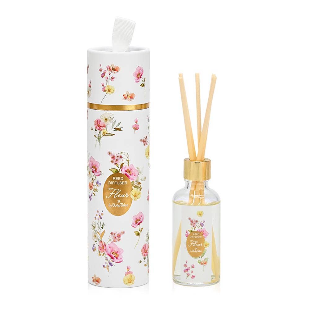 Fleur Pink Reed Diffuser by SoapTales, featuring a clear glass bottle with wooden reeds and a decorative floral cylindrical box in pink, yellow, and lilac hues.