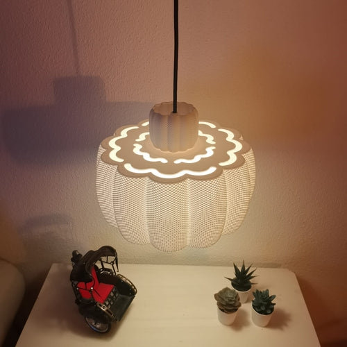pendant lamp with a wavy design on a table with small plants and a model car. View from top.